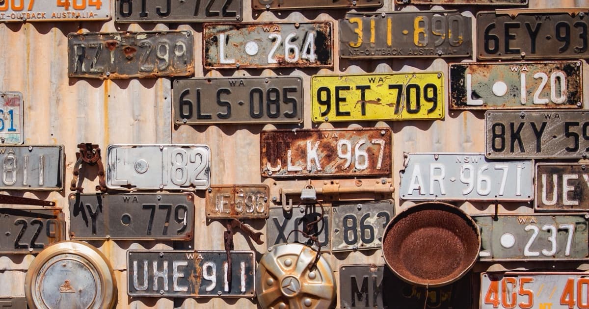 Old Australian number plates nailed to a rusty corrugated iron wall in Leonora, Western Australia